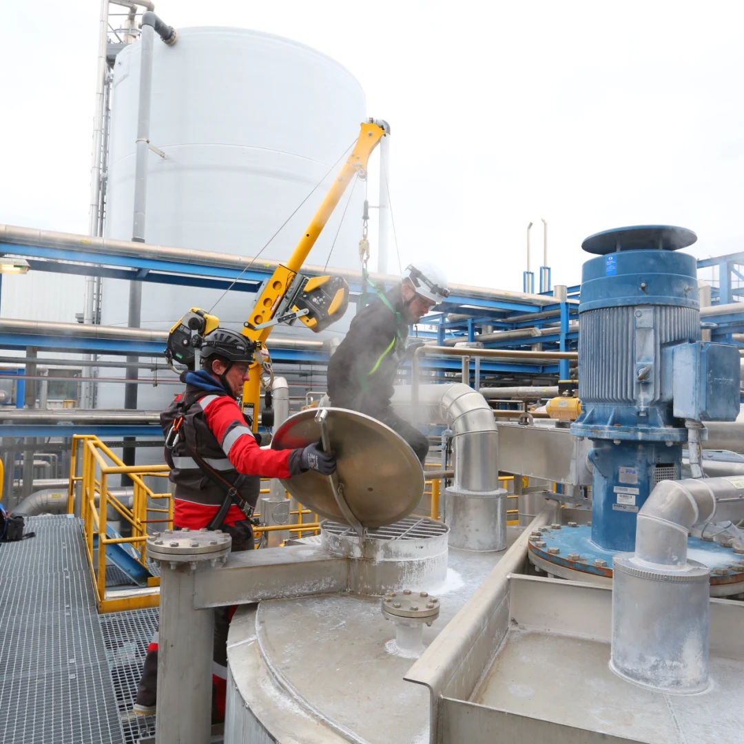 mannen die staan op dak bij een besloten ruimte met helm op en harnas aan