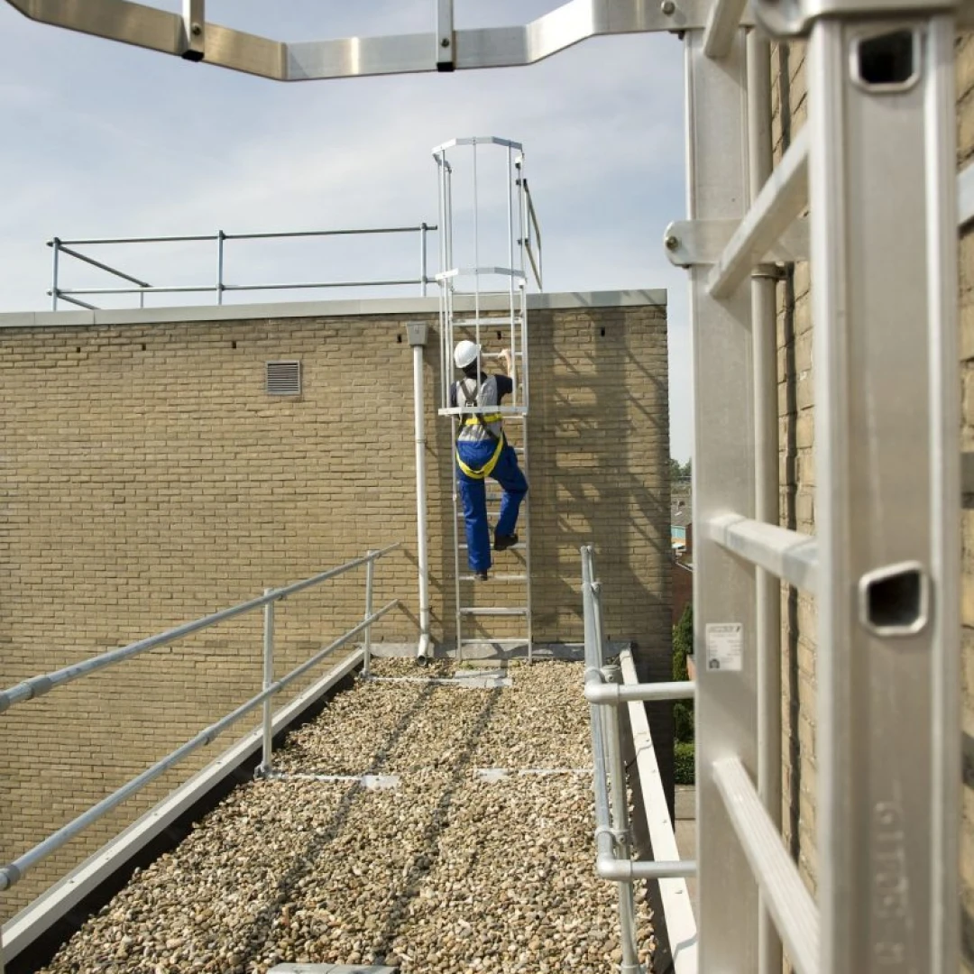 man die klimt op kooiladder op dak