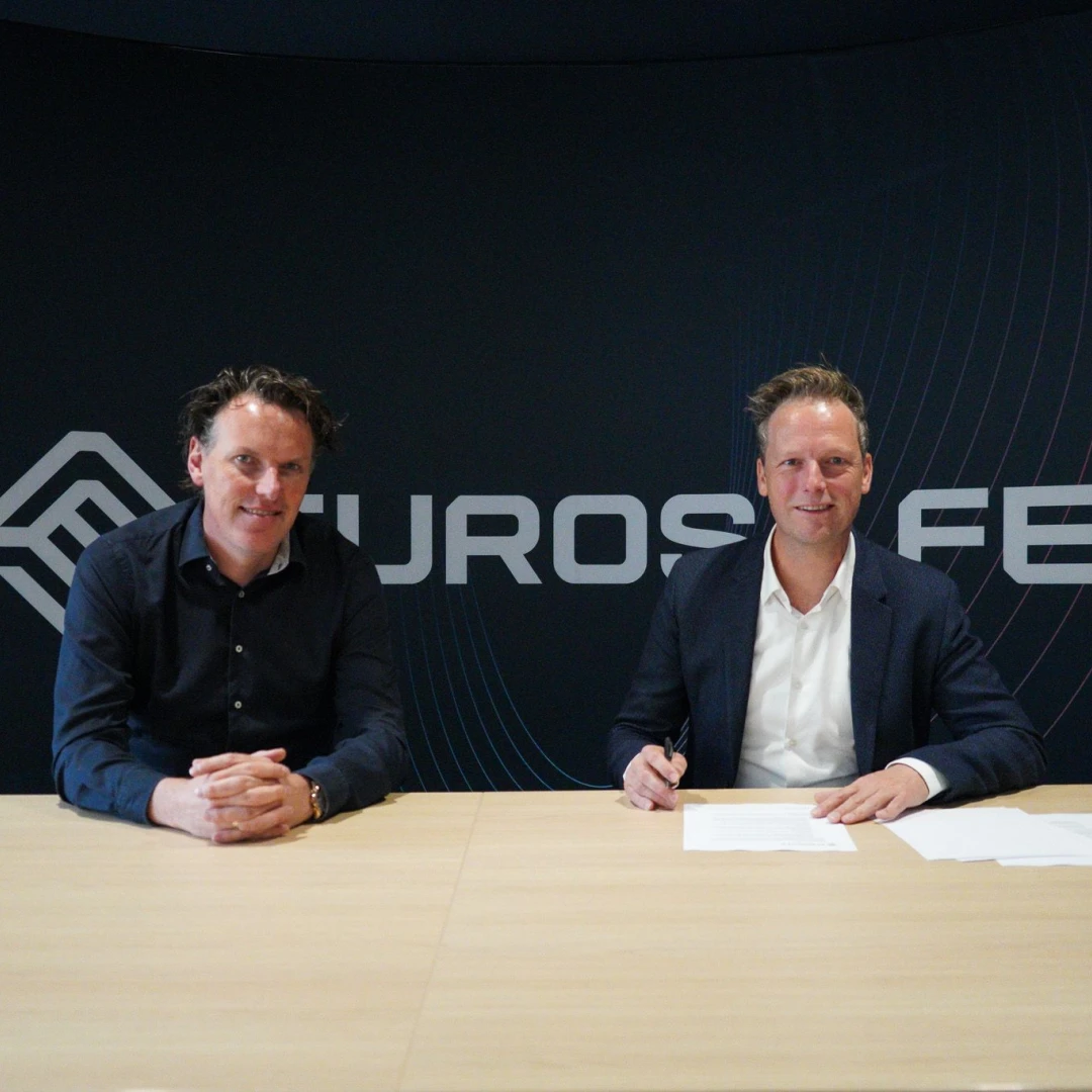 Twee mannen die naast elkaar zitten om een contract te tekenen.