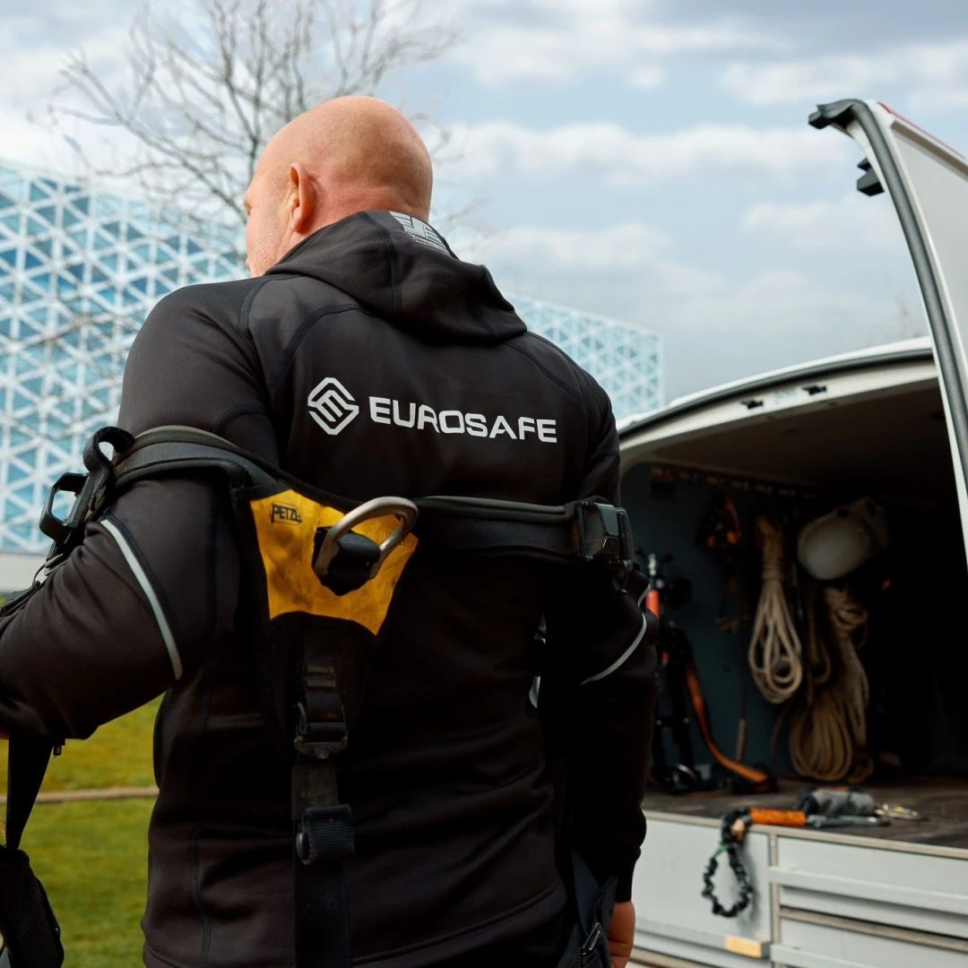 een man die een veiligheidsharnas aantrekt naast een volkswagen bus