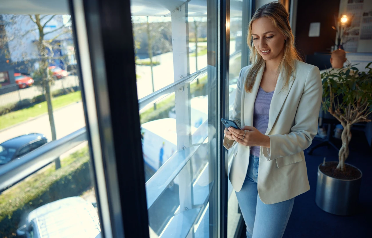 vrouw op telefoon staande bij raam