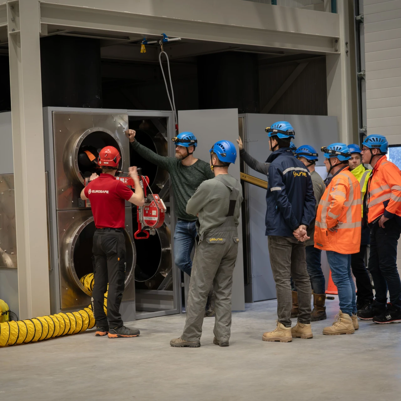 mensen in oefenhal bij besloten ruimte met helm op