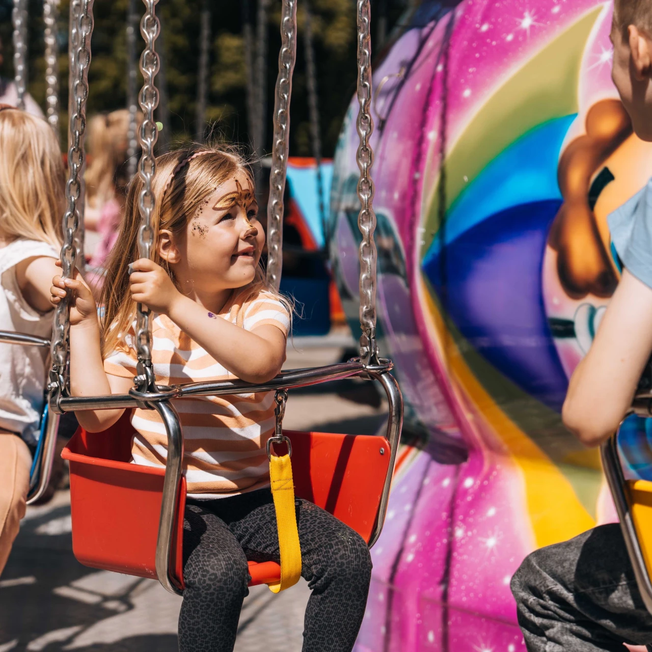 Kinderen die met schmink op hun gezicht in een draaimolen zitten