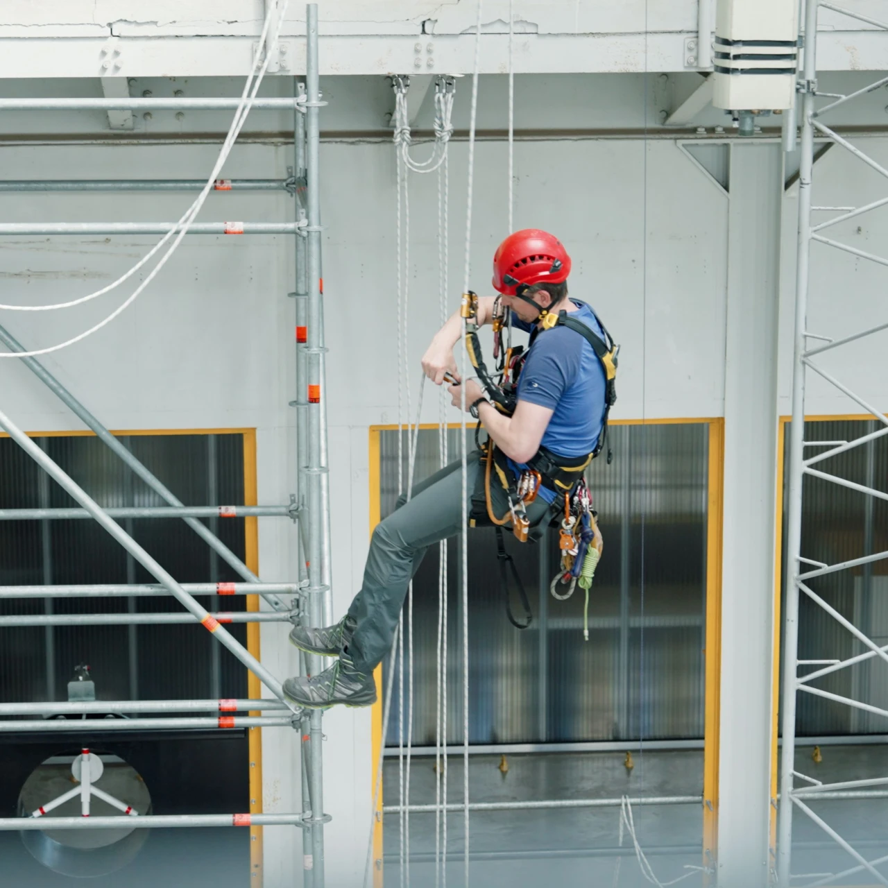 man hangend in touwen op hoogte met helm en harnas
