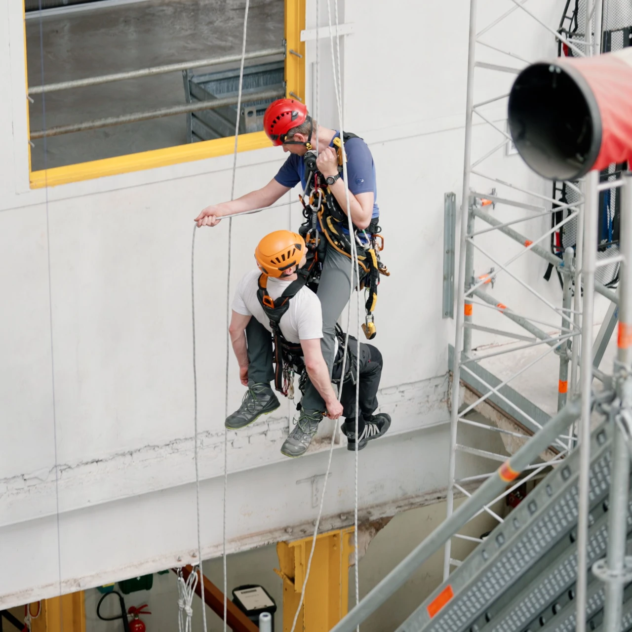 mannen hangend aan touwen op hoogte met harnas en helm