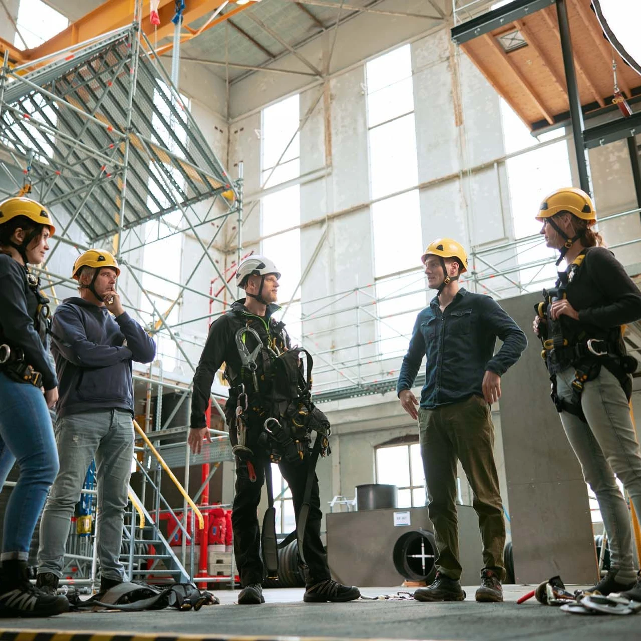 personen in rij in loods met helm en harnas