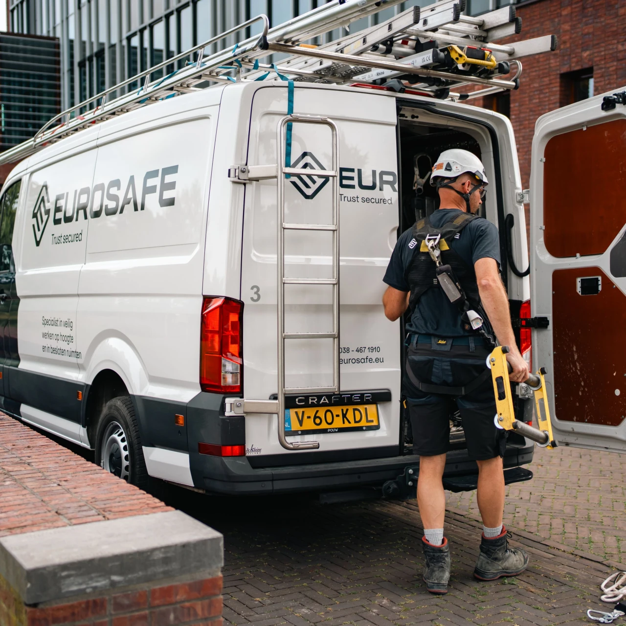 man die staat voor een werkbus met een helm op en gereedschap in zijn hand