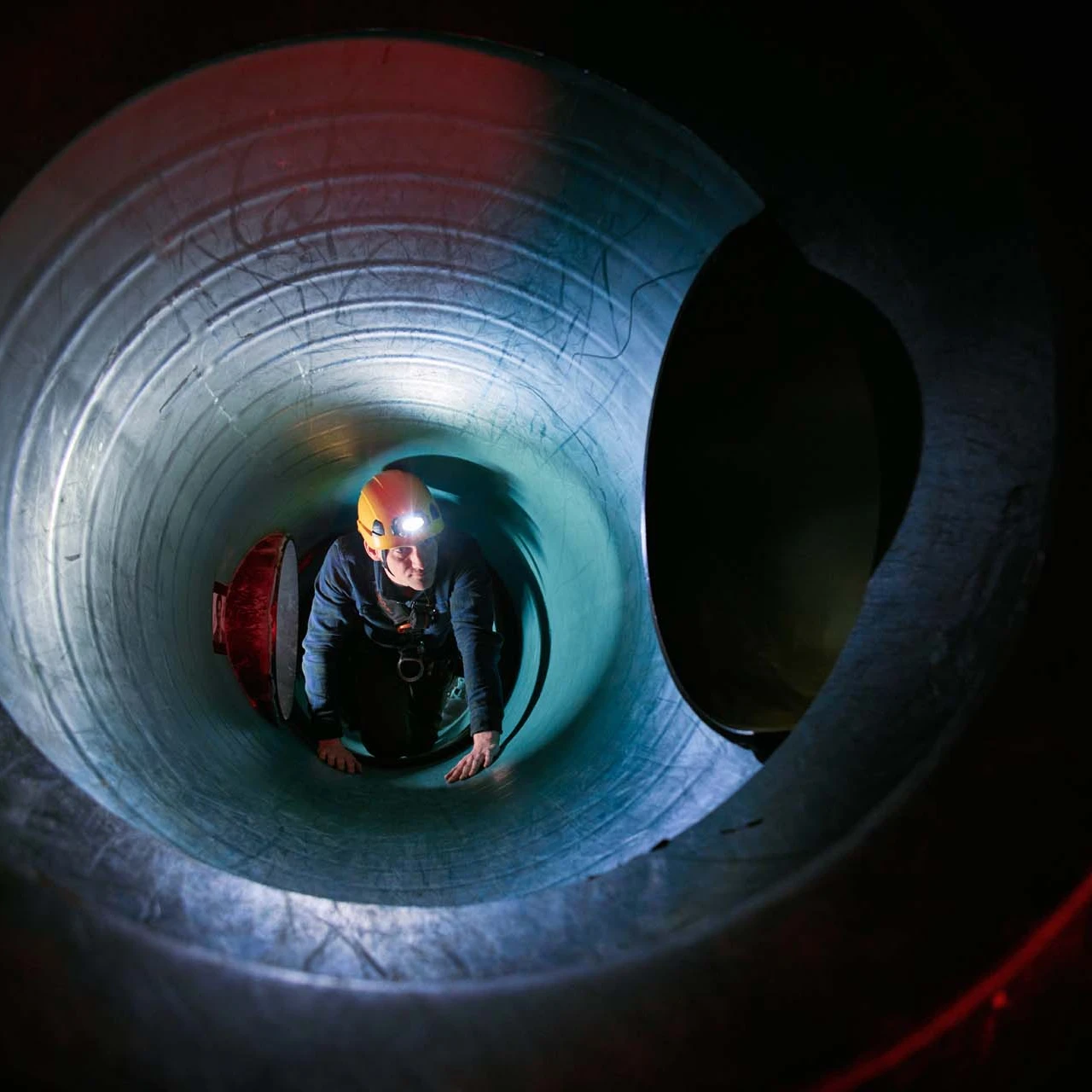man in besloten ruimte met helm en lamp op hoofd