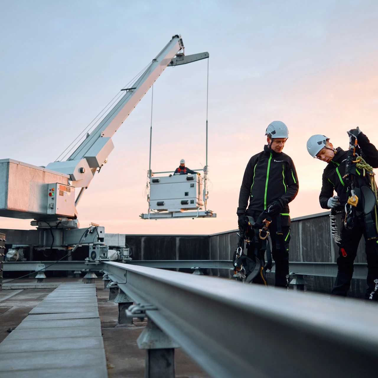twee mannen op dak met helm en harnas met kraan