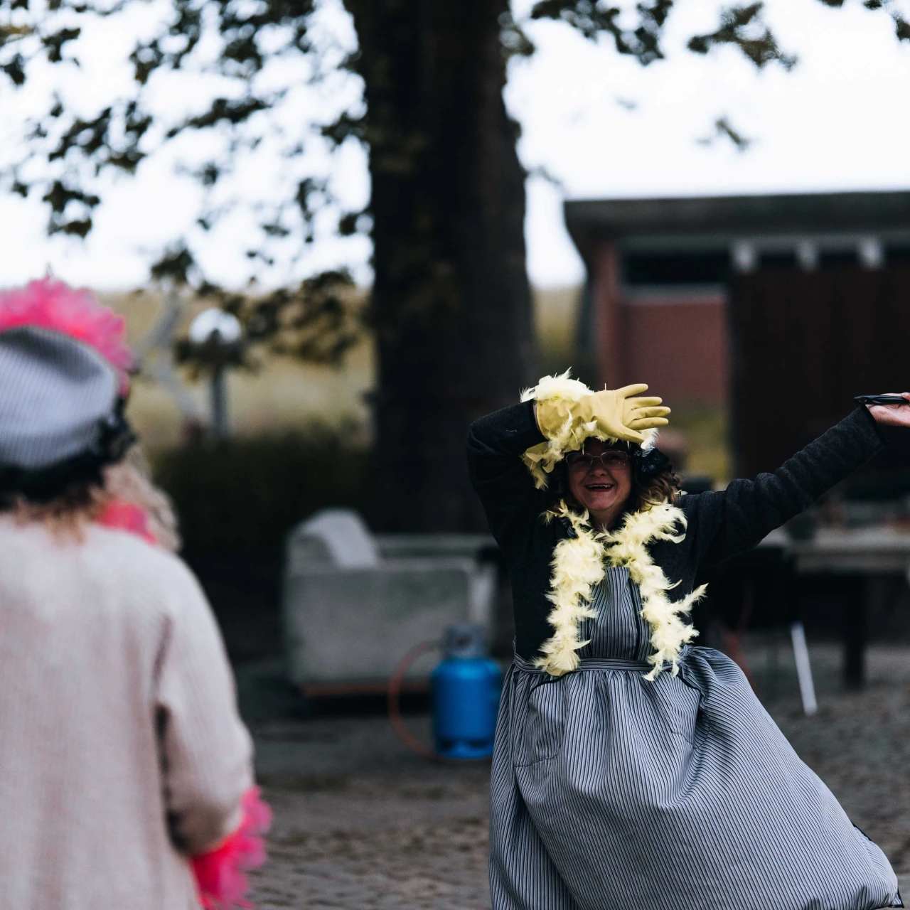 twee vrouwen met groene en roze boa's die zingen en dansen in de buitenlucht