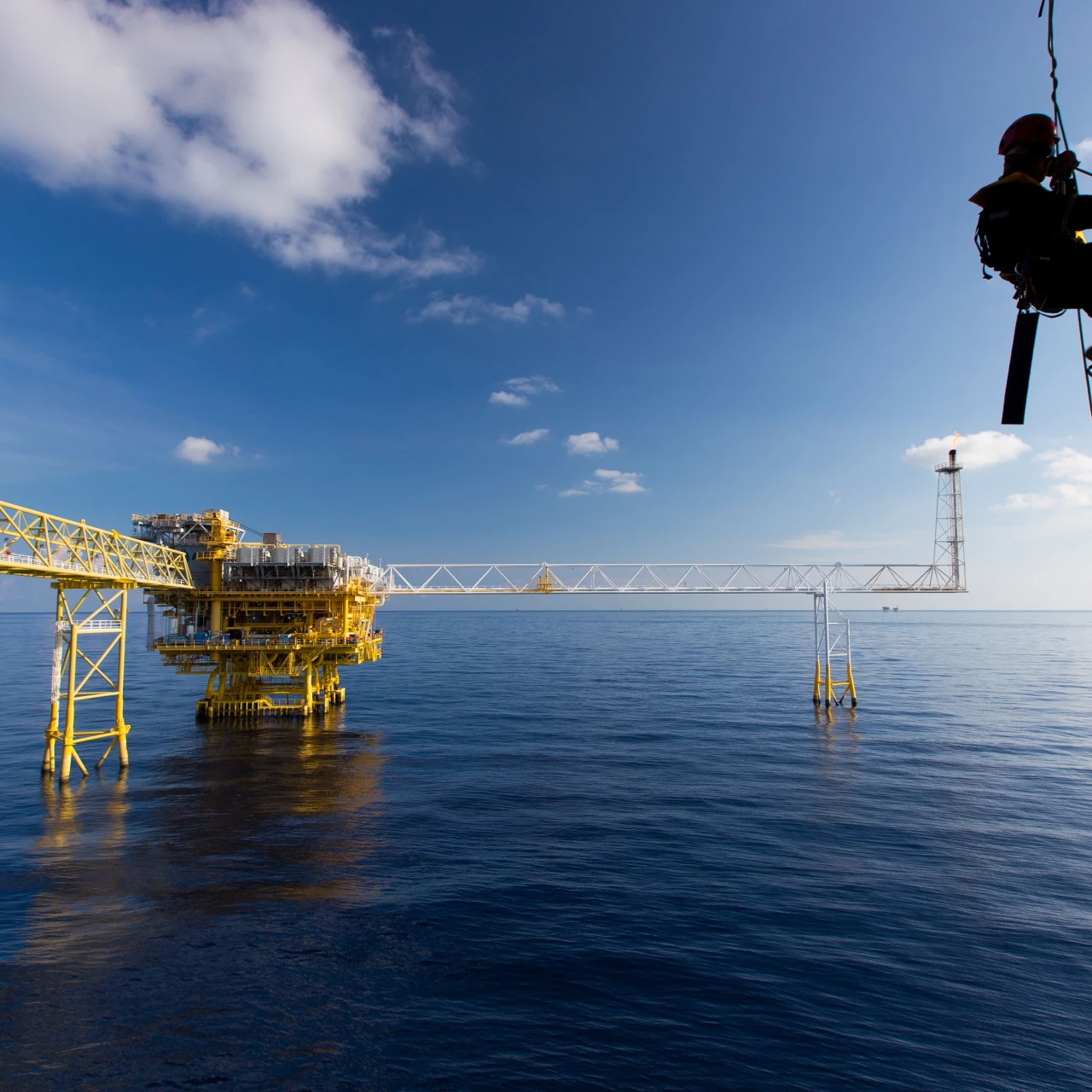 man hangend aan touw bij water met helm