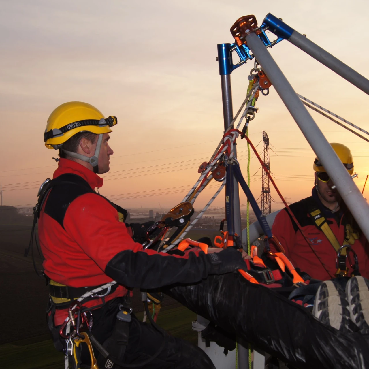 mannen met persoon op brancard op hoogte met harnas aan en helm op