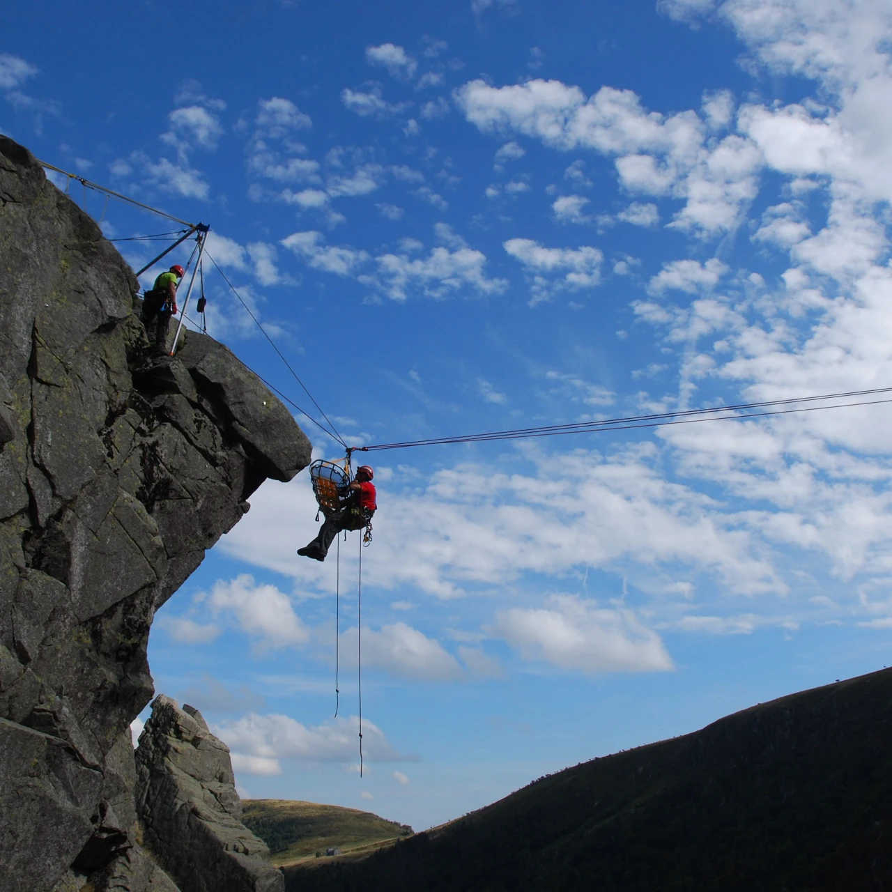 mensen bij rots die iemand redden met brancard en touw