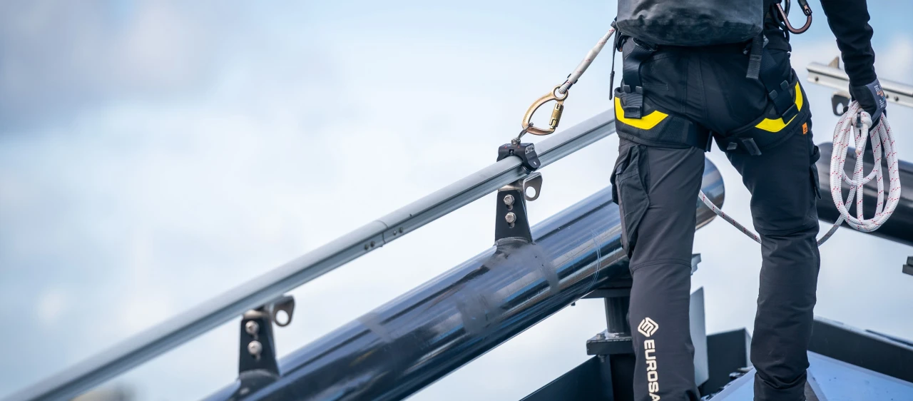 man op dak aan veiligheidslijn met haak en touw