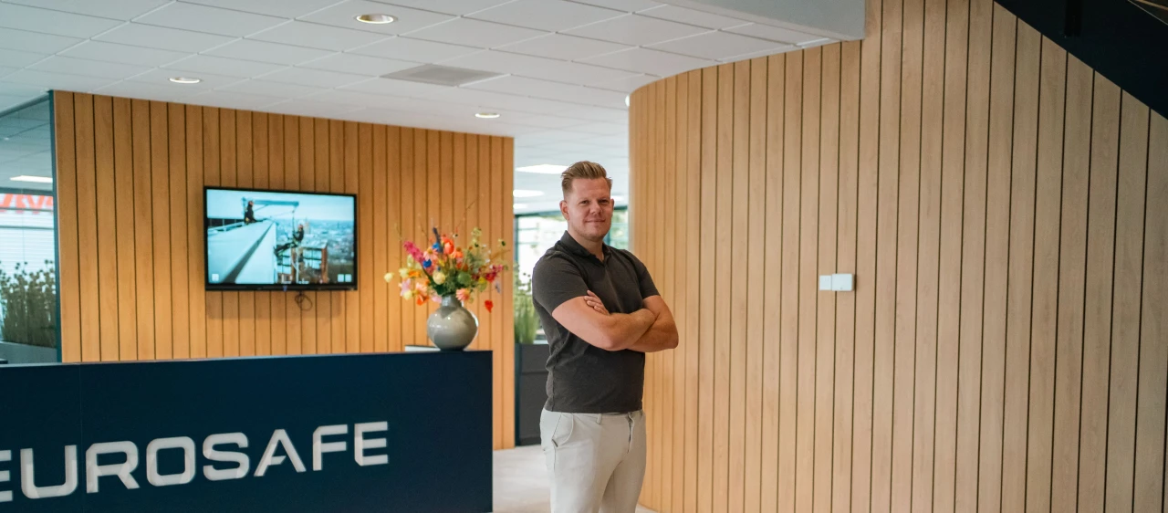 een man die zijn armen over elkaar heeft in een aankomsthal