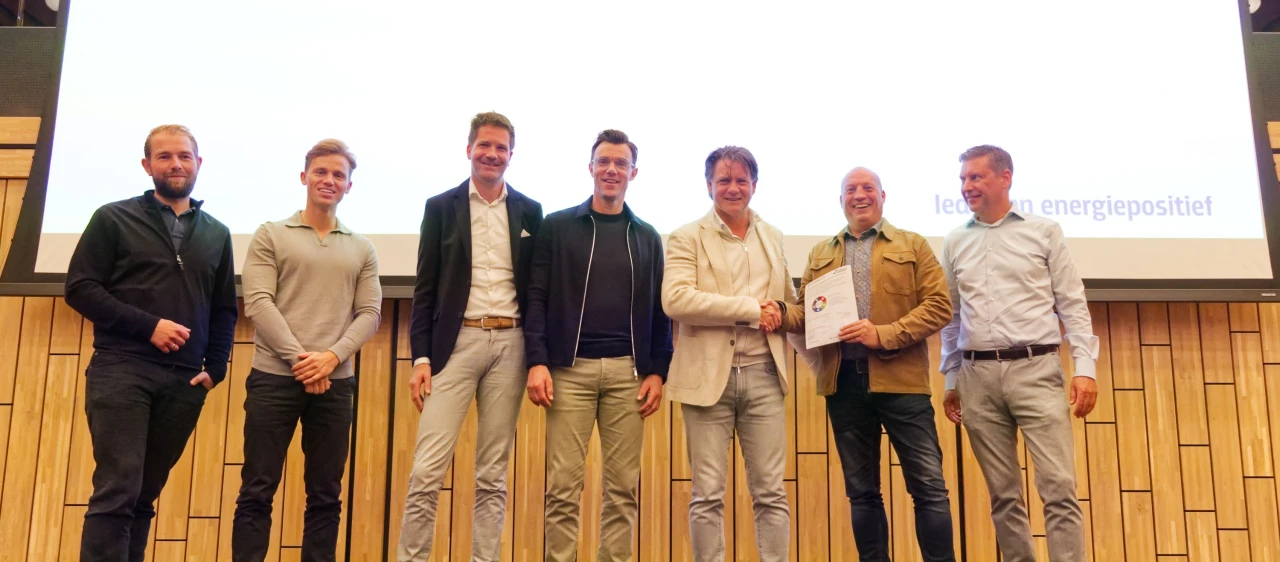 lachende mannen op rij met scherm achter hen