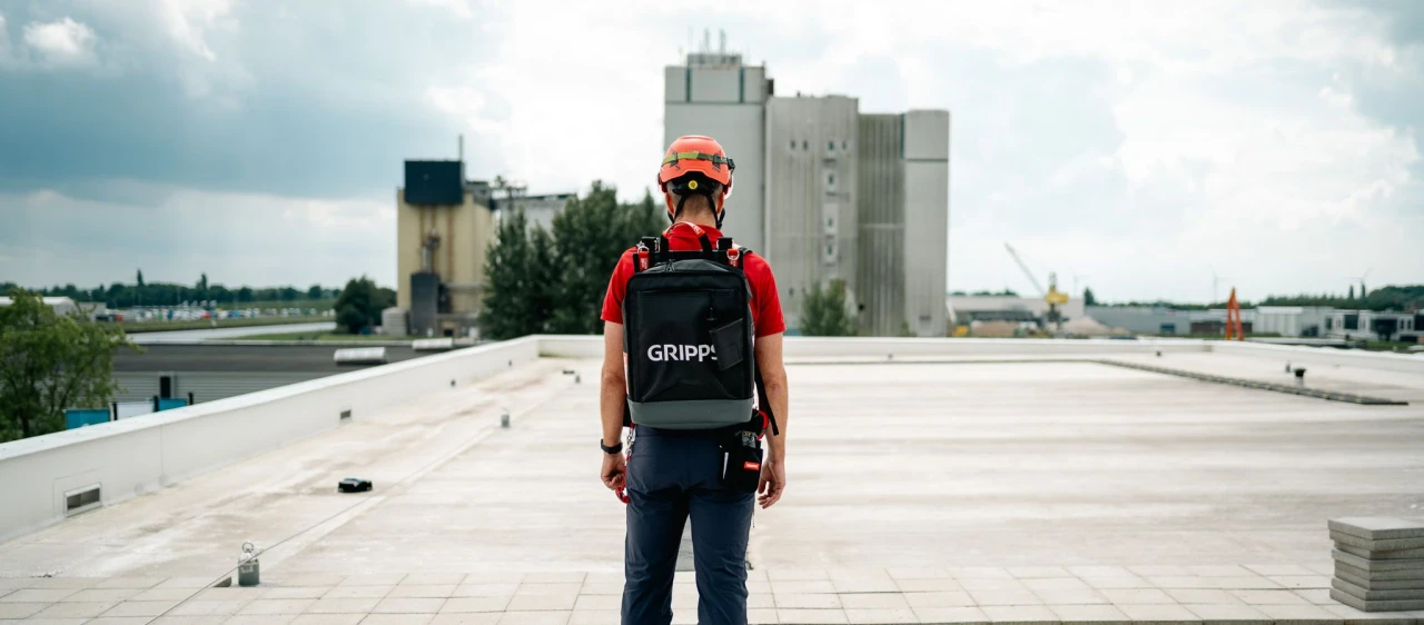 een man die op een dak staat met een gripps rugzak om