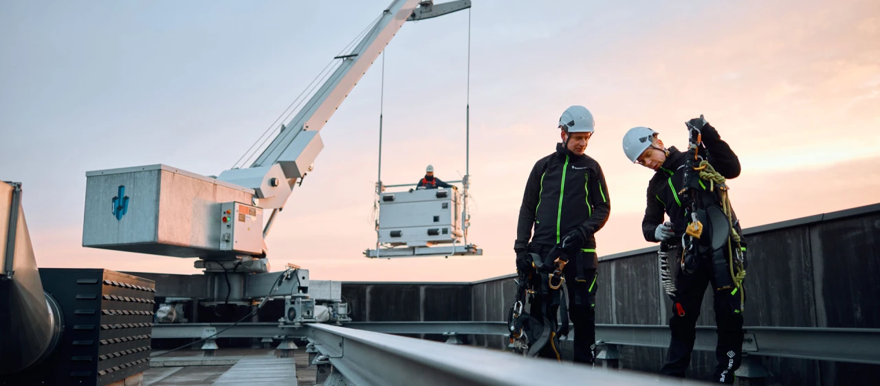 twee mannen op dak met harnas en helm met kraan