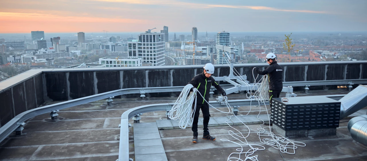 mannen op hoog dak met touw en apparatuur