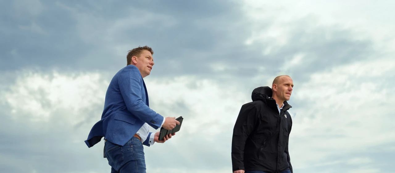 twee mannen die staan op een glazen dak met een jas aan