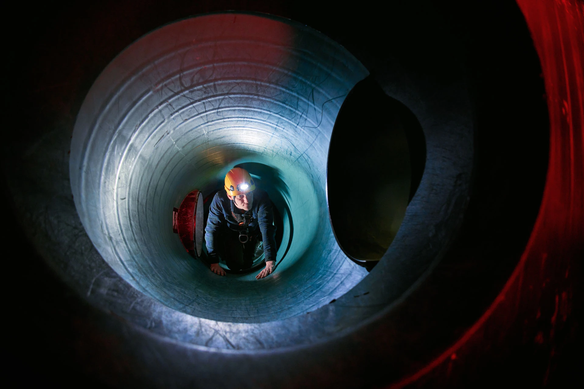 man loopt in besloten ruimte met helm en lamp