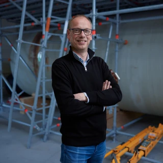 blije man met bril poserend in hal met armen over elkaar