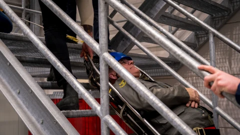 trap met man op brancard die geholpen wordt