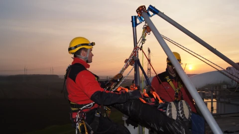 mannen met persoon op brancard op hoogte met harnas aan en helm op