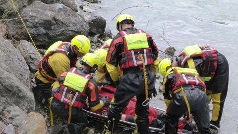 mensen bij het water met helm en reddingsvest persoon aan het redden