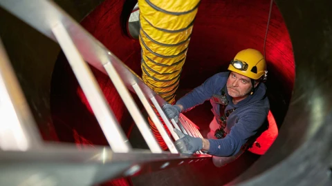 man met ladder en helm in besloten ruimte
