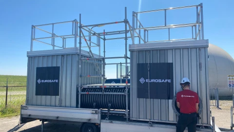 Een man die naast een metalen trailer staat waarin besloten ruimte trainingen kunnen worden gedaan