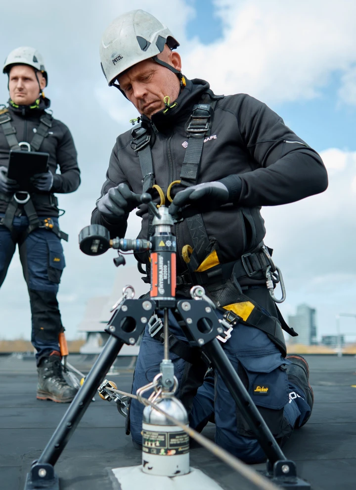 mannen op dak met apparatuur in harnas met helm op