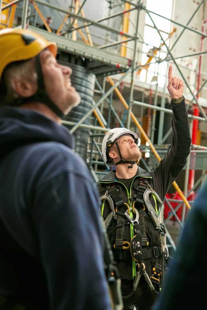 man in beschermingsharnas en helm op die naar boven wijst