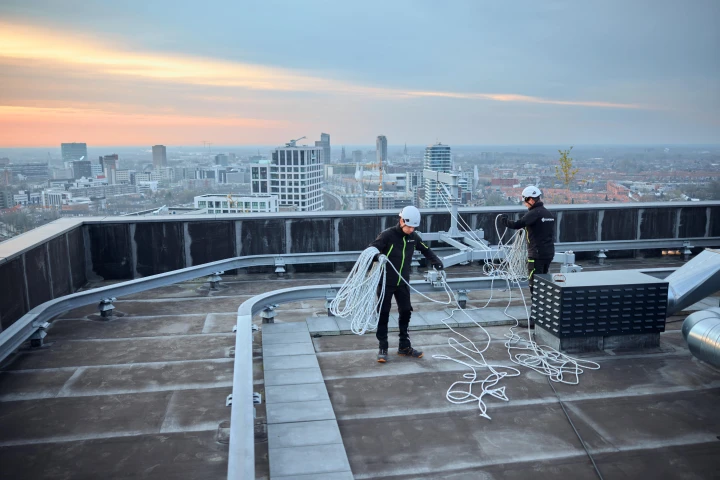 mannen op hoog dak met touw en apparatuur