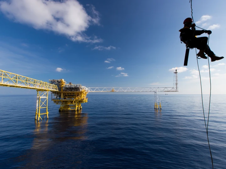 man hangend aan touw bij water met helm