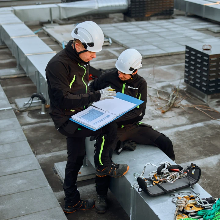 twee mannen met helm en materiaal op dak