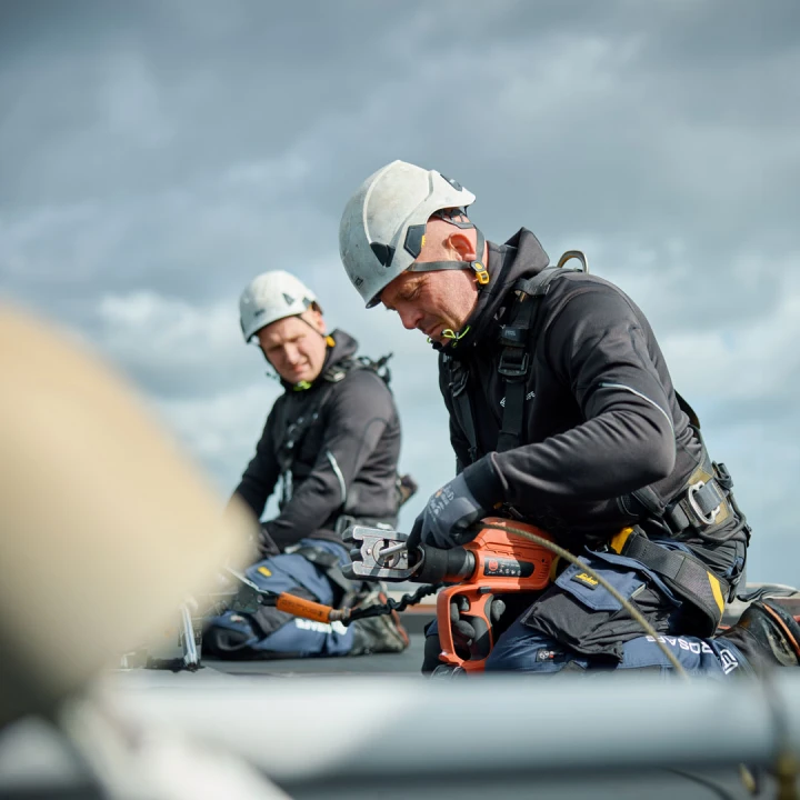 mannen op dak bezig met apparatuur met helm in harnas